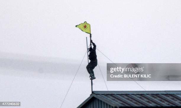Kurdish People's Protection Units fighter unfurls their flag at the Akcakale crossing gate between Turkey and Syria at Akcakale in Sanliurfa province...