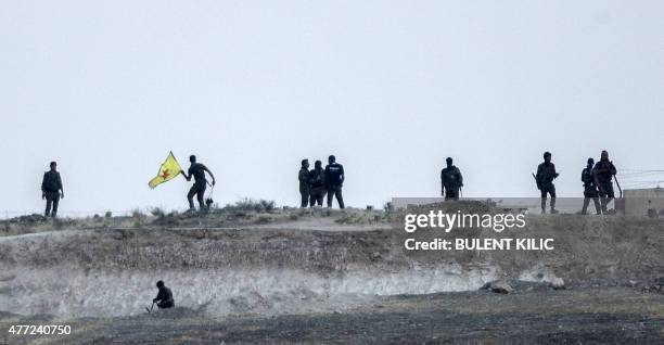Kurdish People's Protection Units fighter holds their movement's flag near the Akcakale crossing gate between Turkey and Syria at Akcakale in...