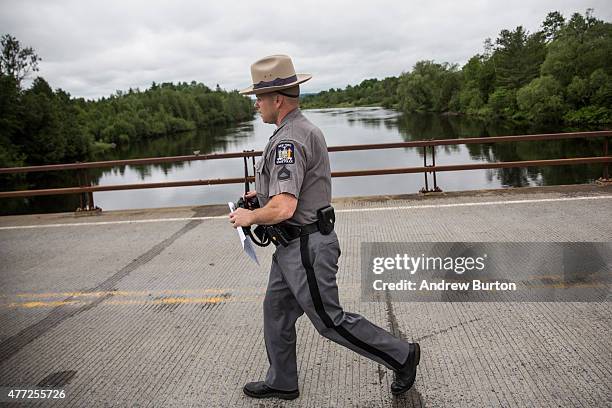 New York state trooper walks across a bridge while searching for two escaped convicts on June 15, 2015 outside Dannemora, New York. The two convicted...