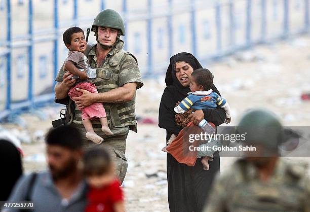 Turkish soldier carries a Syrian refugees boy as they walk to cross into Turkey at Akcakale border gate in Sanliurfa province, Turkey, June 15, 2015....