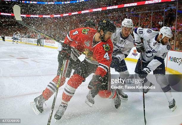 Niklas Hjalmarsson of the Chicago Blackhawks fights for the puck against Jonathan Drouin and Brenden Morrow of the Tampa Bay Lightning in the first...