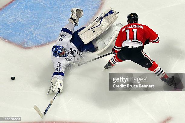 Ben Bishop of the Tampa Bay Lightning dives for the puck against Andrew Desjardins of the Chicago Blackhawks during the second period in Game Six of...