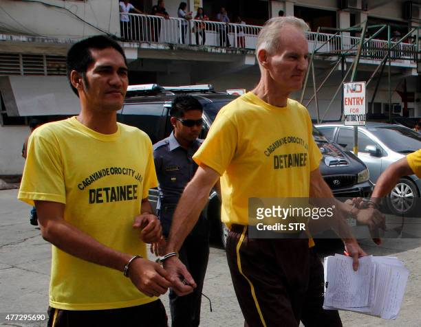 Peter Scully of Australia , accused of raping and trafficking two girls in the Philippines, leaves the court handcuffed to another inmate after his...