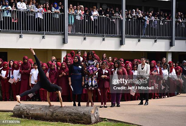 Student performs a gymnastic routine as young women hold the American flag as they greet US First Lady Michelle Obama in the courtyard before an...