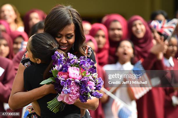 Student gives flowers to, embraces and welcomes with other young students US First Lady Michelle Obama in the courtyard before an event as part of...