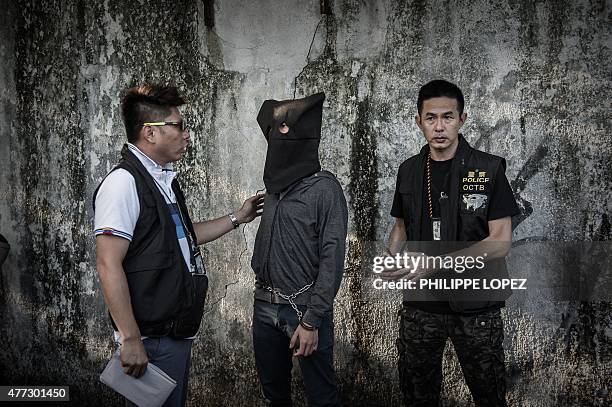 Suspect is escorted by policemen during a crime reconstruction in the east-coast district of Sai Kung in Hong Kong on June 16, 2015 a day after...