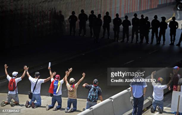 Demonstrators kneel in front of riot police during a protest against the government of Venezuelan President Nicolas Maduro in Caracas on March 8,...