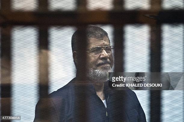 Egypt's ousted Islamist president Mohamed Morsi stands behind the bars during his trial in Cairo on June 16, 2015. An Egyptian court upheld a death...