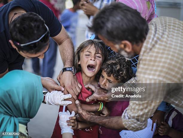 Syrian girl cries as she is vaccinated before crossing into Turkey from Akcakale Border Gate in Sanliurfa, Turkey on June 16, 2015. Hundreds of...