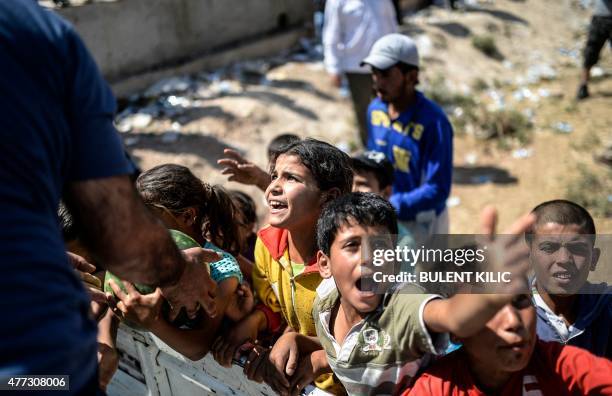 Syrians attend a distribution of watermelons near the Akcakale crossing gate between Turkey and Syria at Akcakale in Sanliurfa province on June 16,...