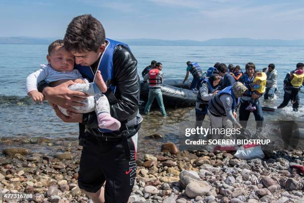 Refugee from Afghanistan carries a baby on arrival on the shores of Lesbos near Skala Skamnias, Greece on June 2, 2015. Lesbos, the Greek vacation...