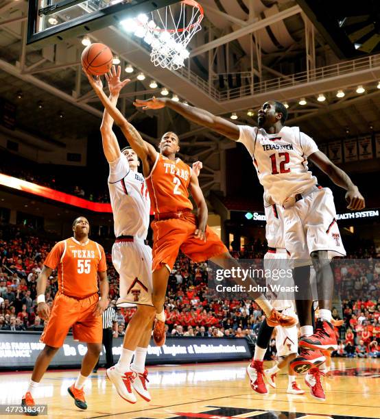 Demarcus Holland of the Texas Longhorns shoots the ball over Dejan Kravic of the Texas Tech Red Raiders and Kader Tapsoba of the Texas Tech Red...