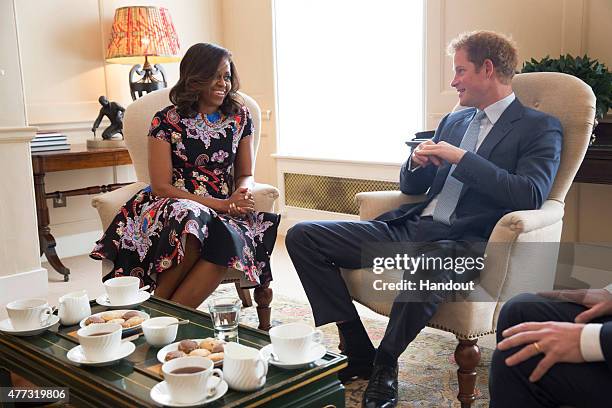 In this handout photo provided by The White House, US First Lady Michelle Obama meets Prince Harry at Kensington Palace on June 16, 2015 in London,...