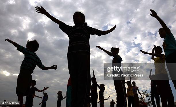 Indian swimming students perform yoga to warm up during swimming coaching on Satish Rao's annual free summer camp at the Yamuna river at Sangam, the...