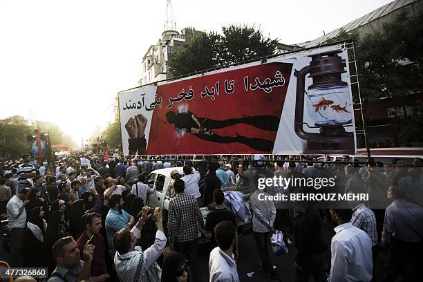 Iranians display a large poster depicting a handcuffed diver and reading in Farsi: "Martyrs are the pride of human beings forever" at Tehran's...