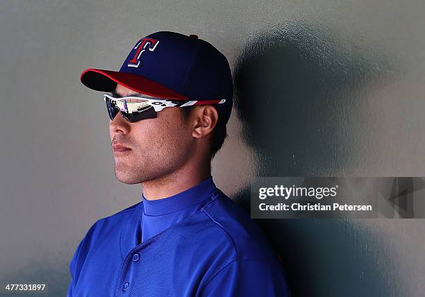 Kensuke Tanaka of the Texas Rangers sits in the duogut during the spring training game against the Los Angeles Dodgers at Surprise Stadium on March...