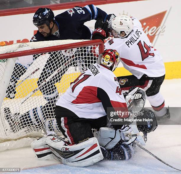 Eric Tangradi of the Winnipeg Jets crashes into goaltender Craig Anderson of the Ottawa Senators in third-period action in an NHL game at the MTS...