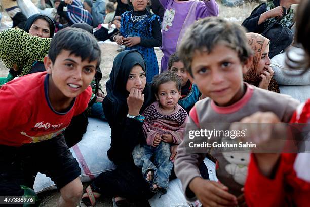 Syrian refugees wait after crossing into Turkey at the Akcakale border gate on June 16 in Sanliurfa province, Turkey. Kurdish fighters in Syria have...