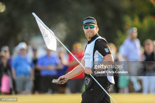 John Wood, caddie to Hunter Mahan, removes a pin flag on the 16th hole during the third round of the World Golf Championships-Cadillac Championship...