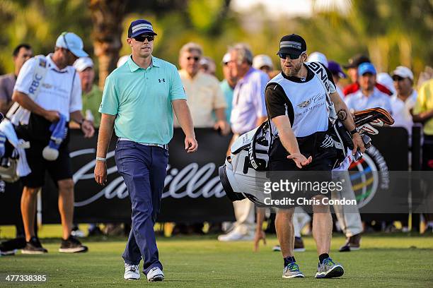 Hunter Mahan speaks with his caddie John Wood after teeing off on the 17th hole during the third round of the World Golf Championships-Cadillac...