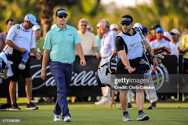 Hunter Mahan speaks with his caddie John Wood after teeing off on the 17th hole during the third round of the World Golf Championships-Cadillac...