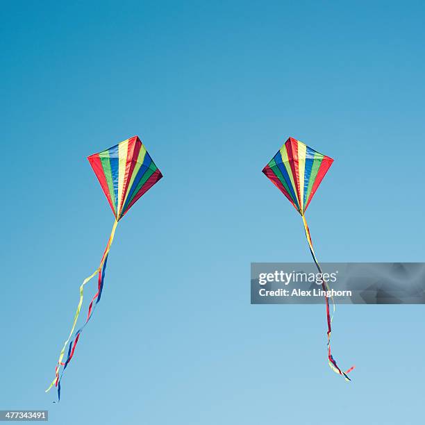 two colourful kites flying in blue sky - 2 objetos cometas fotografías e imágenes de stock
