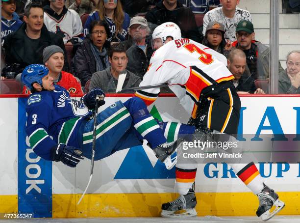 Ladislav Smid of the Calgary Flames checks Kevin Bieksa of the Vancouver Canucks during their NHL game at Rogers Arena March 8, 2014 in Vancouver,...