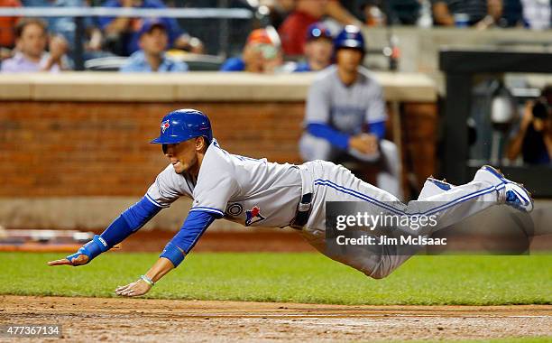 Ryan Goins of the Toronto Blue Jays dives home for an eighth inning run on a sacrifice fly against the New York Mets at Citi Field on June 16, 2015...