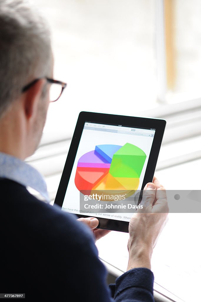 Man looking at pie chart on tablet