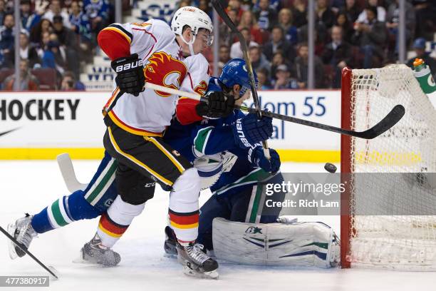 Sean Monahan of the Calgary Flames tries to knock the puck into the net while battling with Chris Tanev of the Vancouver Canucks during the third...