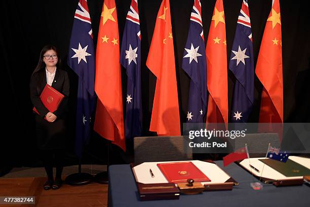 Woman holding a copy of the Free Trade Agreement stands next to National flags of China and Australia during a signing ceremony on June 17, 2015 in...