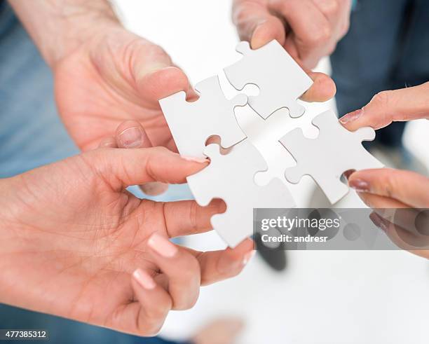 business group putting pieces of a puzzle together - model kit stock pictures, royalty-free photos & images