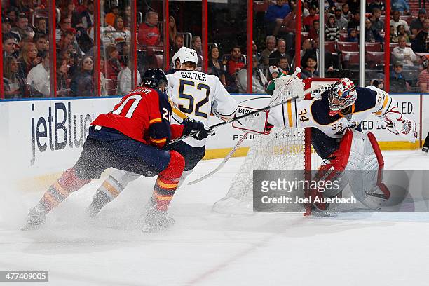 Michal Neuvirth looks back as Alexander Sulzer of the Buffalo Sabres and Sean Bergenheim of the Florida Panthers skate after a loose puck at the BB&T...