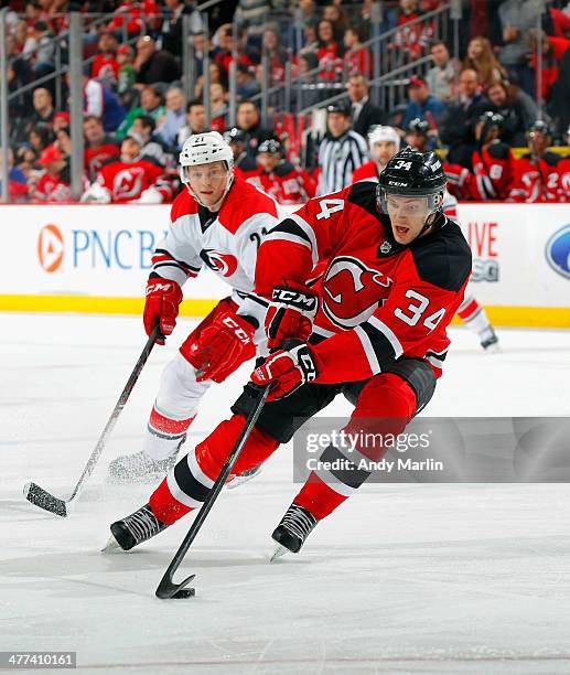 Jon Merrill of the New Jersey Devils controls the puck while being defended by Drayson Bowman of the Carolina Hurricanes during the game at the...