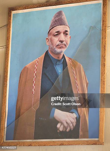 Picture of Afghan President Hamid Karzai with broken glass hangs on the wall in an Afghan National Police outpost on March 9, 2014 near Kandahar,...