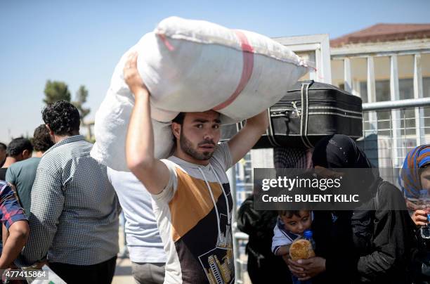 Syrian refugees wait with their belongings prior to go back to the northern Syrian town of Tal Abyad at the Turkish border post of Akcakale, the...