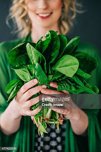 young woman holding spinach leafs salad - spinazie stockfoto's en -beelden