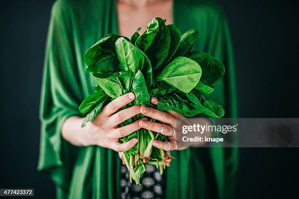 joven mujer sosteniendo espinaca leafs ensalada - espinaca fotografías e imágenes de stock