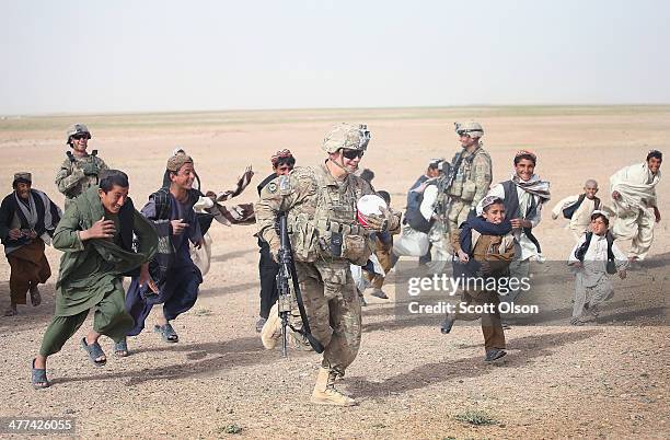 Taylor Burcham with the U.S. Army's 4th squadron 2d Cavalry Regiment gives a soccer ball to children during a patrol through a village on March 9,...