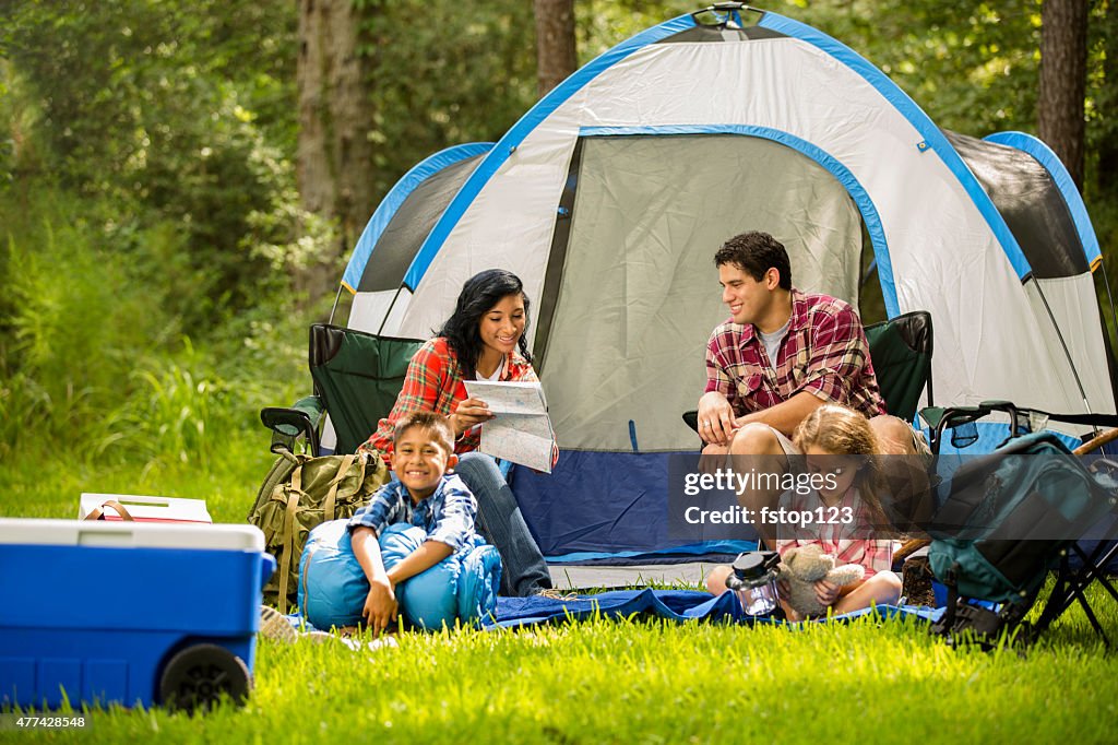 Family camping outdoors in forest. Tent, supplies. Summer vacation.