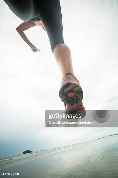 low angle view of woman running on beach - eén trede stockfoto's en -beelden