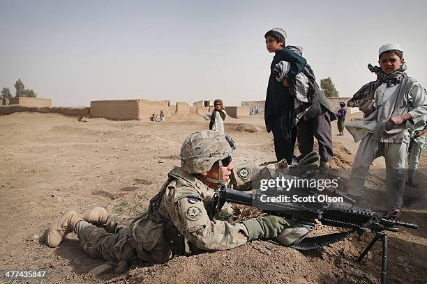 Children stand by as SPC Wilmer Bolivar from Pembroke Pines, Florida with the U.S. Army's 4th squadron 2d Cavalry Regiment keeps watch during a...