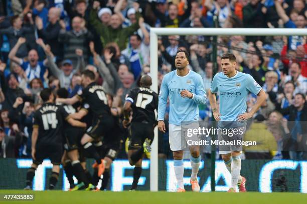 Joleon Lescott and Javi Garcia look dejected as Wigan celebrate the second goal during the FA Cup Quarter-Final match between Manchester City and...