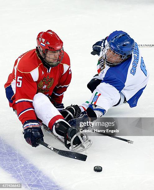 Vasilii Varlakov of Russia is tackled by Gianluca Cavaliere of Italy during the Ice Sledge Hockey Preliminary Round Group B match between Russia and...