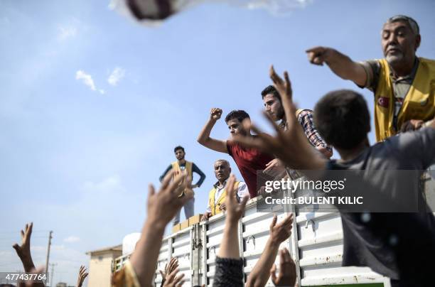 Syrian refugees catch aid supply near the Turkish border post of Akcakale, province of Sanliurfa, on June 17, 2015. The first Syrian refugees...