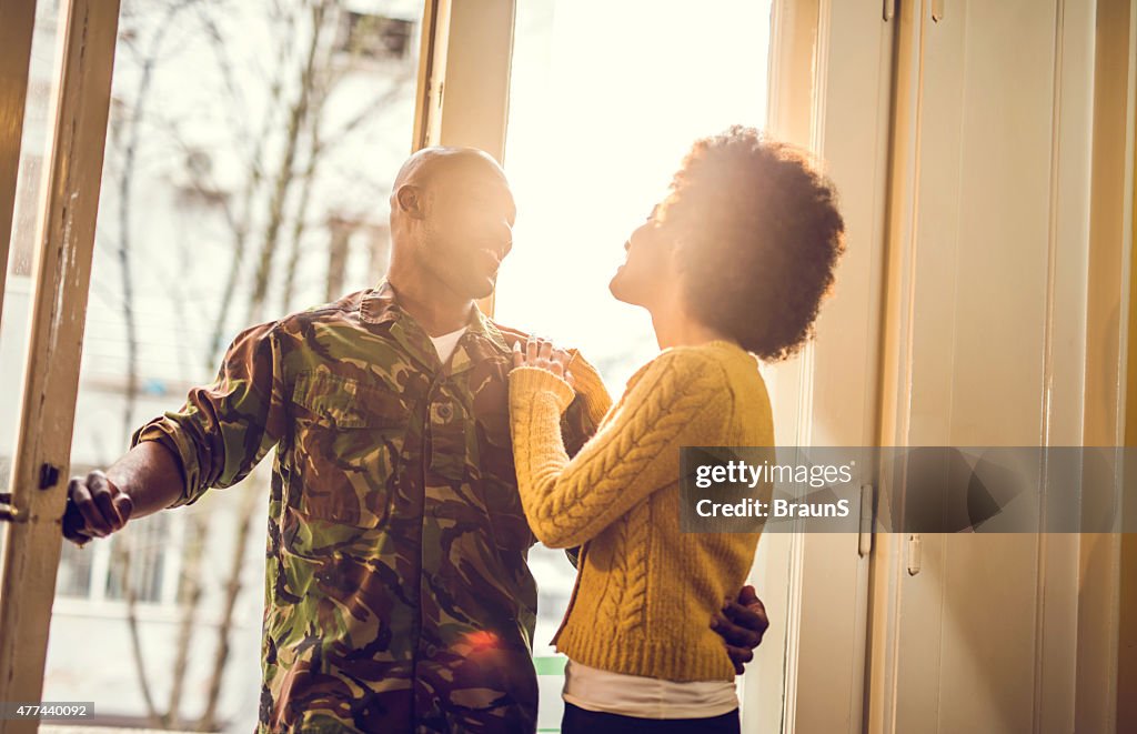 Soldado americano africano feliz coming home para a sua mulher.