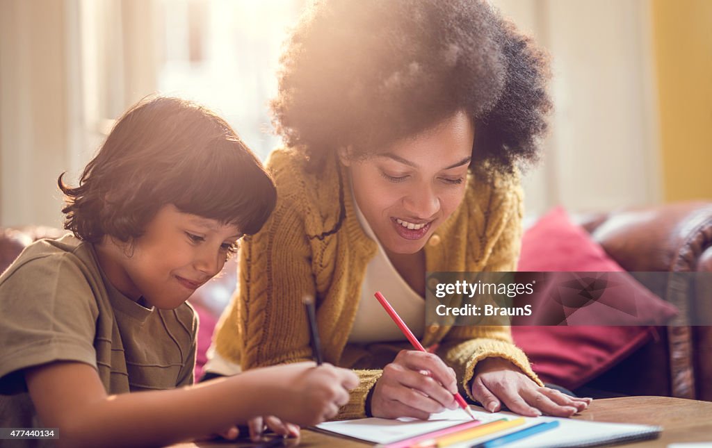 Smiling African American mother and son coloring together.