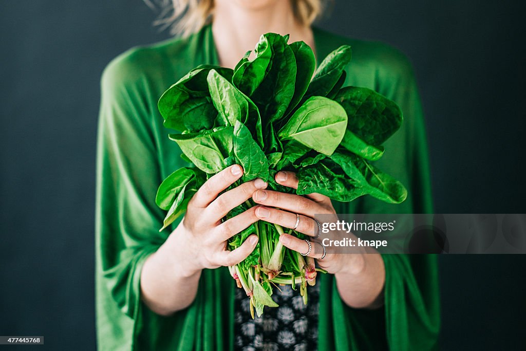 Joven mujer sosteniendo espinaca leafs ensalada
