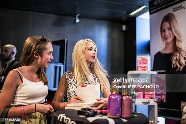 French blogger Marie Lopez, aka EnjoyPhoenix, stands by a fan during a signing of her first book "Enjoy Marie" on June 17, 2015 in a cultural store...