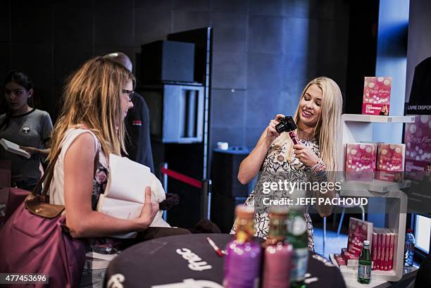 French blogger Marie Lopez, aka EnjoyPhoenix, takes a picture of a fan during a signing of her first book "Enjoy Marie" on June 17, 2015 in a...